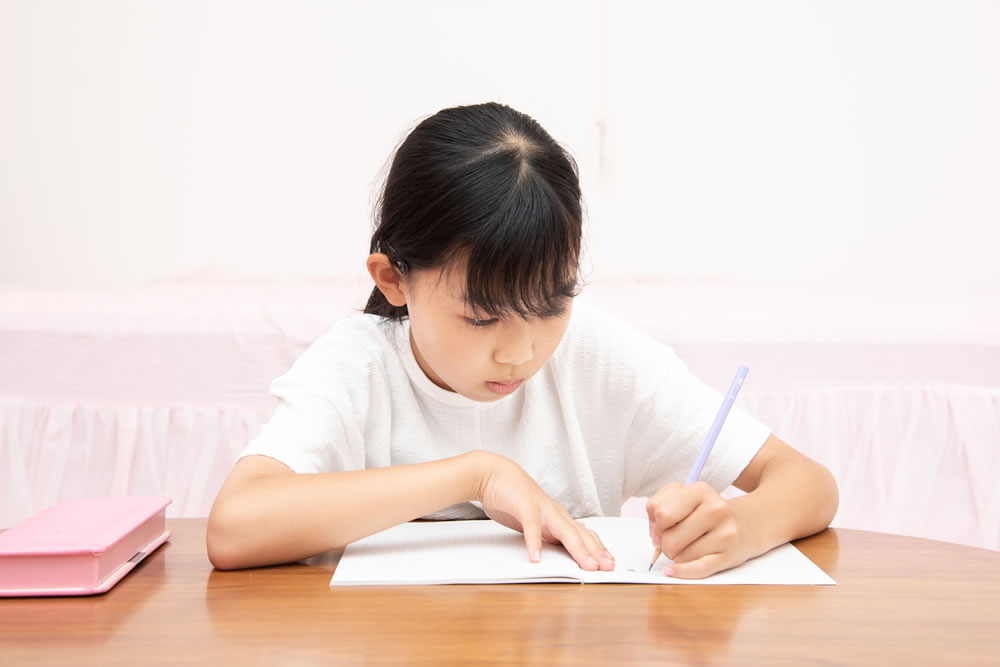 机に向かって勉強している小学生